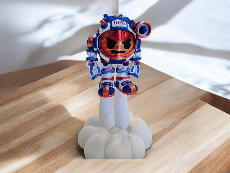 May include: A 3D printed figurine of a red, white and blue robot with an angry face. The robot is standing on a white cloud-shaped base.