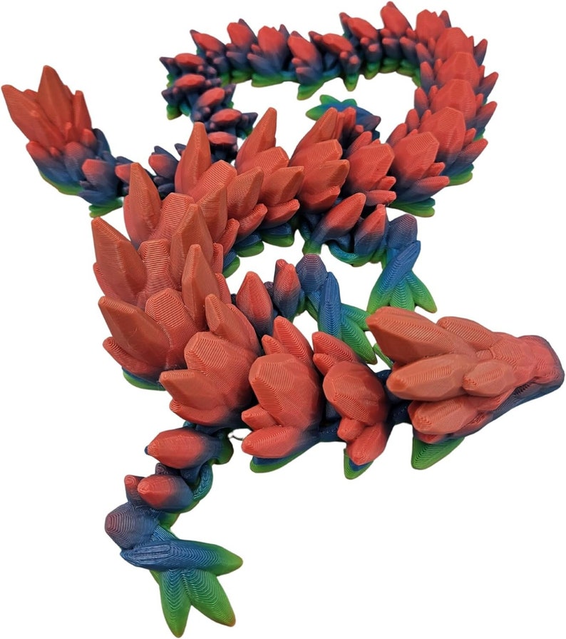 K&ouml;nnte beinhalten: Eine 3D-gedruckte Drachenfigur mit einem rot-blau-gr&uuml;nen Farbschema. Der Drache besteht aus vielen kleinen, spitzen Kristallen.