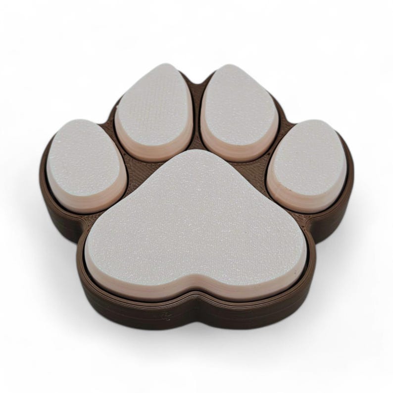 May include: A brown and white paw-shaped item. The item is a paw print design with five pads. The pads are white and the surrounding border is brown. The item is likely a coaster or decorative piece.