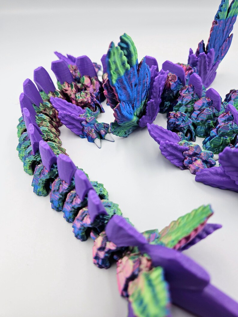 May include: A 3D printed dragon figurine with iridescent purple, green, and blue scales. The dragon is curled up in a defensive posture with its wings spread out.