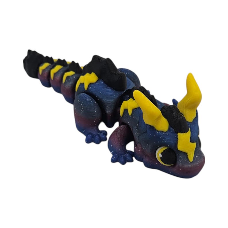 K&ouml;nnte beinhalten: Eine bewegliche Drachenfigur. Der Drache hat einen dunkelblauen K&ouml;rper mit einem galaxieartigen Muster, gelben blitzf&ouml;rmigen Details und H&ouml;rnern. Der Bauch des Drachen geht in ein tiefes Rot &uuml;ber.