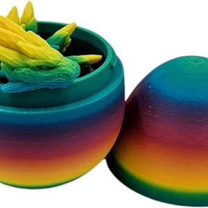 May include: A rainbow-coloured plastic egg with a green lid, open to reveal a set of small, green and yellow dinosaur figurines inside.