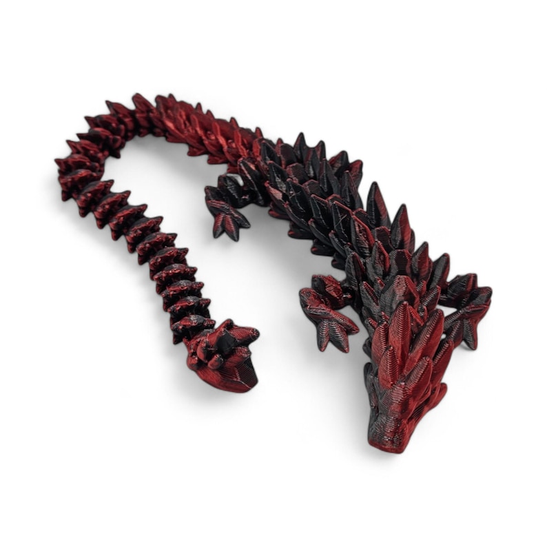 May include: A 3D printed dragon figurine with a black and red color scheme. The dragon is curled up with its tail wrapped around its body.