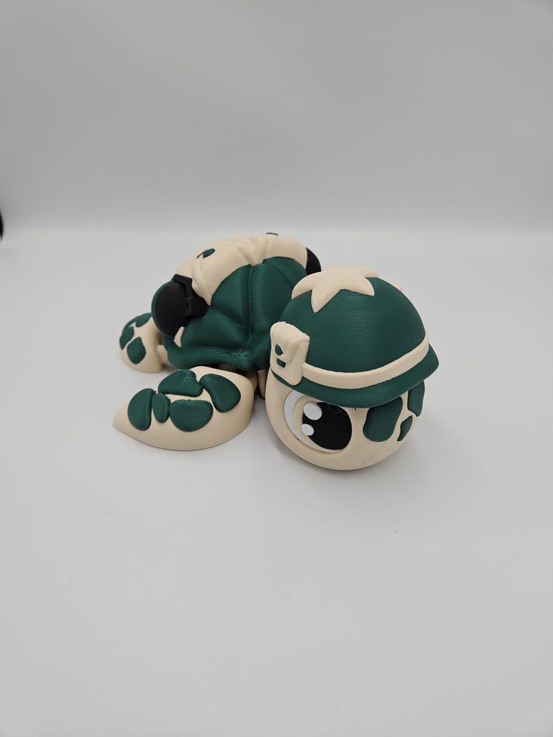 Pode incluir: Figura de tartaruga artesanal com carapa&ccedil;a e cabe&ccedil;a verde escuro, e detalhes em branco sujo. A tartaruga tem olhos grandes e um design divertido. Um objeto decorativo charmoso.