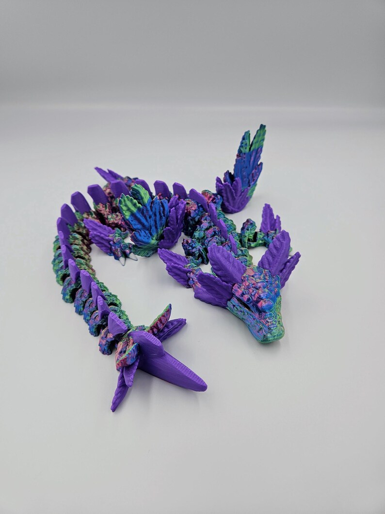 May include: A 3D printed dragon figurine with a purple and green iridescent finish. The dragon is segmented and has wings.