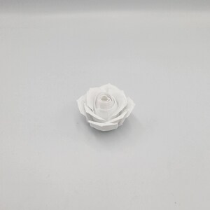 May include: A single, pristine white rose, centered against a plain white background. The rose is fully bloomed, showcasing detailed petal formation. The image highlights the delicate beauty of the flower, perfect for floral arrangements or crafts.