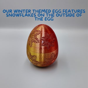 K&ouml;nnte beinhalten: Ein rotes und goldenes eif&ouml;rmiges Ornament mit einem Schneeflockenmuster. Das Ornament ist aus Kunststoff und hat eine gl&auml;nzende Oberfl&auml;che.
