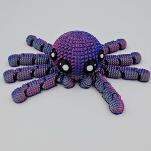 Op de afbeelding: Een kleine, 3D-geprinte octopus met een roze en blauwe kleurverloop. De octopus heeft acht tentakels en grote, zwarte ogen.