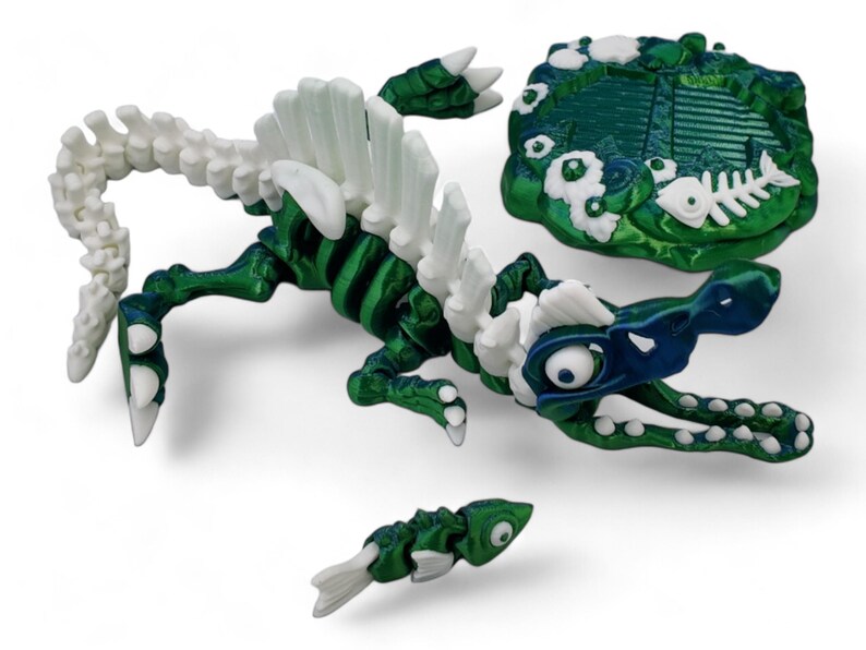 May include: A green and white skeleton of a sea monster with a blue and white head. The monster is holding a small green and white fish in its mouth. The monster is on a green and white rock with white flowers.