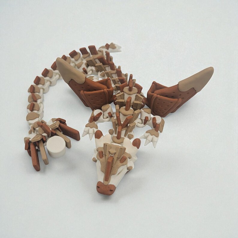以下が含まれることがあります： 主にベージュと茶色で構成された、ドラゴンの骨格の精巧な彫刻。モデルは、分割された体、翼、詳細な頭部を備えています。 ドラゴンは、横たわっているかのようにポーズをとっており、複雑なディテールが施されています。