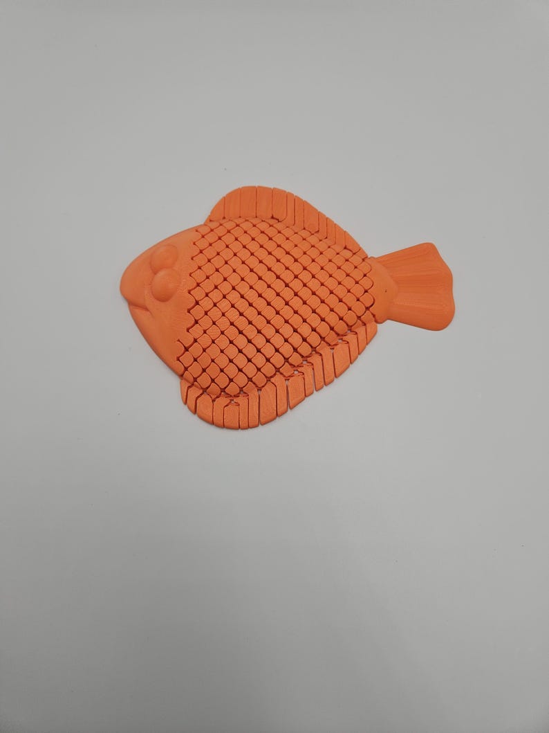 May include: An orange, stylized fish figurine with a textured body and fins. The fish has a rounded shape with a detailed scale pattern and is likely made of plastic or a similar material. The figurine is a decorative item.