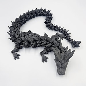 May include: A black, 3D printed dragon figurine with a spiky, textured surface. The dragon is posed in a crawling position with its head raised.