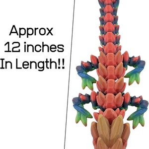 K&ouml;nnte beinhalten: Eine 3D-gedruckte, mehrfarbige Drachenfigur, etwa 30 cm lang. Der Drache ist rot, orange, gelb, gr&uuml;n und blau.