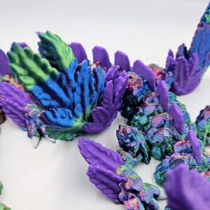 May include: A close-up of a 3D printed dragon's scales, featuring a vibrant iridescent finish with shades of purple, blue, green, and pink.