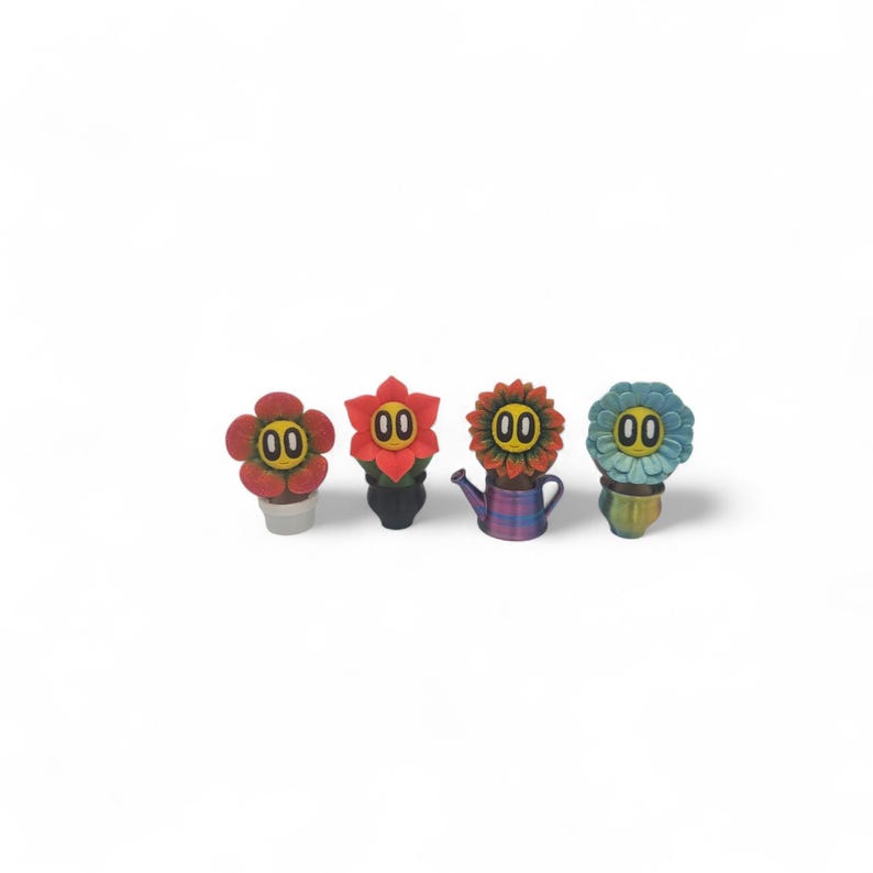 May include: Four whimsical flower-shaped figurines with smiling faces and the number "00" on their faces. The flowers are red, orange, and blue, and are in small pots or a watering can. The background is white.