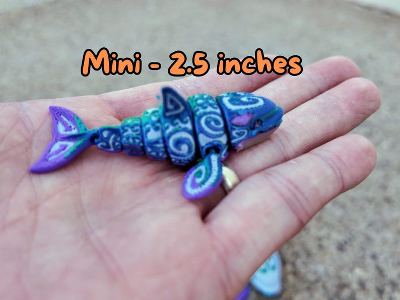 May include: A small, blue and green patterned shark figurine, approximately 2.5 inches long. The figurine is made of plastic and has a detailed design. "Mini - 2.5 inches" is written in orange text on the image.