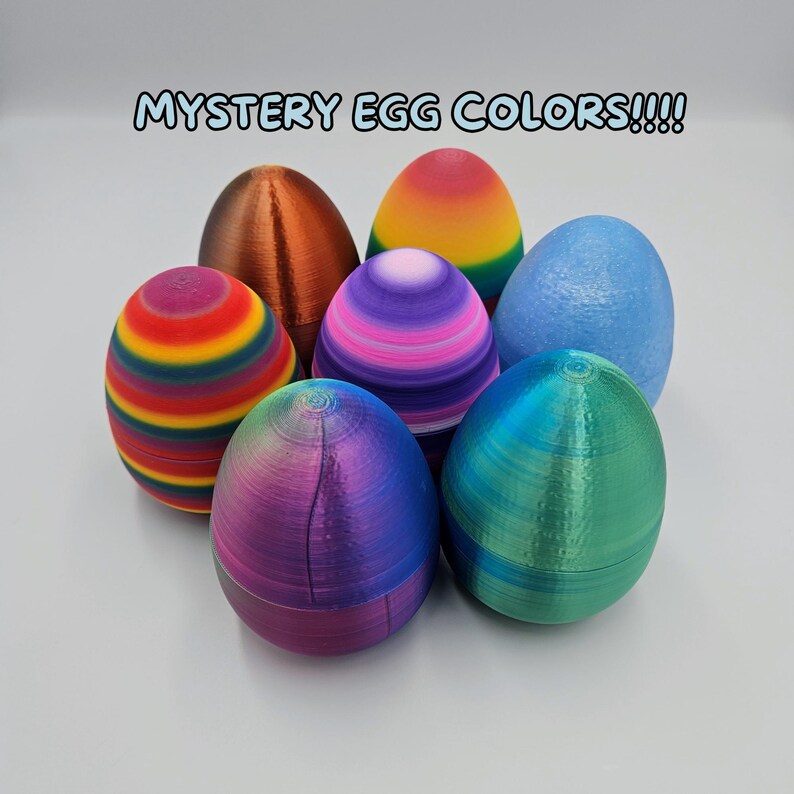 K&ouml;nnte beinhalten: Sechs bunte Ostereier mit verschiedenen Mustern und Texturen. Die Eier sind in einem Kreis auf einer wei&szlig;en Oberfl&auml;che angeordnet. Der Text "MYSTERY EGG COLORS!!!!" ist in blauer Schrift &uuml;ber den Eiern geschrieben.