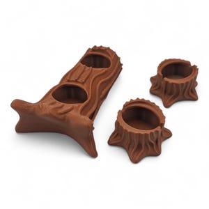 May include: Three brown tree stump-shaped candle holders. One tall holder has two openings, and two smaller holders are also included. The holders are made of a textured material, and are designed to resemble tree stumps.