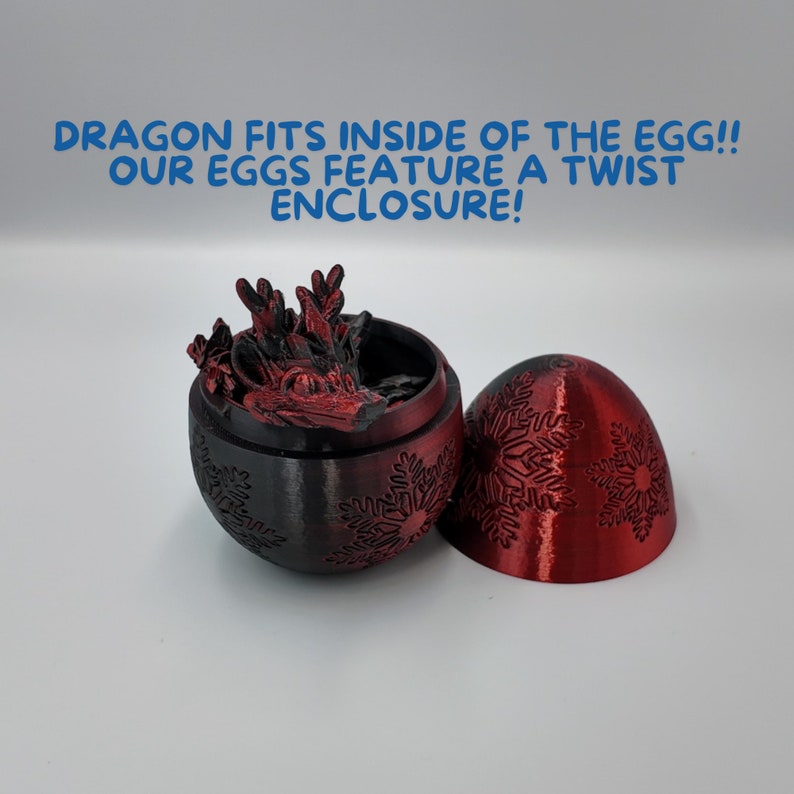 K&ouml;nnte beinhalten: Eine rote und schwarze Drachenfigur passt in ein rotes Ei mit Schneeflockenmuster. Das Ei ist offen und der Drache ist im Inneren sichtbar. Der Text "DRAGON FITS INSIDE OF THE EGG!! OUR EGGS FEATURE A TWIST ENCLOSURE!" steht &uuml;ber dem Ei.