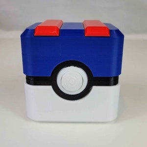 May include: A blue and white 3D printed Pokemon Pokeball storage box with a red lid. The box is designed to look like a Pokeball.