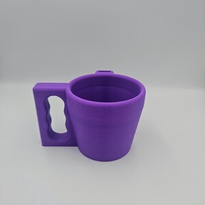 Pu&ograve; includere: Una tazza viola con una superficie strutturata e un manico. Il manico &egrave; rettangolare con un'apertura curva. La tazza &egrave; cilindrica con una forma leggermente affusolata. La tazza &egrave; realizzata in un materiale solido.