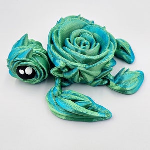 May include: A 3D printed sea turtle figurine with a green and blue color gradient. The turtle's shell is shaped like a rose.