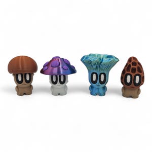 May include: Four whimsical mushroom figurines in brown, purple, blue, and tan. Each figure has a mushroom cap and a body with large, round eyes. The mushrooms are arranged in a row against a white background, showcasing their unique designs.