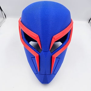 May include: A blue and red 3D printed mask with a textured surface. The mask has a pointed chin and a wide, flat top.