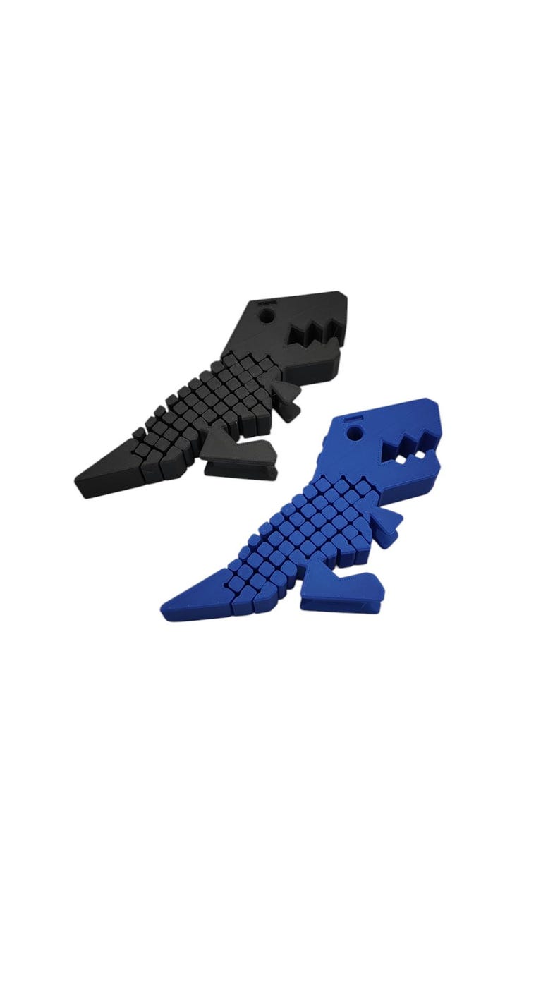 Puede incluir: Dos objetos con forma de dinosaurio, uno negro y otro azul, se muestran sobre un fondo blanco. Los dinosaurios tienen un dise&ntilde;o geom&eacute;trico, con una serie de peque&ntilde;os cuadrados que forman sus cuerpos y dientes irregulares.