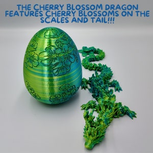 Pu&ograve; includere: Un drago stampato in 3D di colore verde e blu con dettagli di fiori di ciliegio. Il drago &egrave; arrotolato in un cerchio, con la testa che riposa sulla coda. Il drago &egrave; fatto di un materiale liscio e lucido.