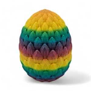 May include: A colorful, egg-shaped decorative object. The object is made up of layers of rainbow-colored, petal-like shapes. The colors transition from yellow to green, blue, purple, and red. The object is standing on a white surface.