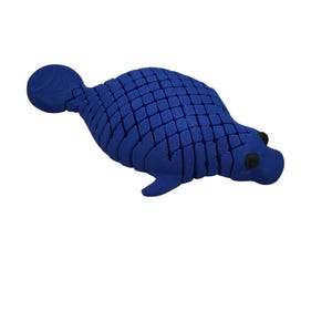 Puede incluir: Figura de foca azul segmentada con ojos negros y cola redondeada. El cuerpo de la foca est&aacute; hecho de numerosos trozos rectangulares peque&ntilde;os, lo que le da un aspecto texturizado. La figura est&aacute; sobre un fondo blanco liso.