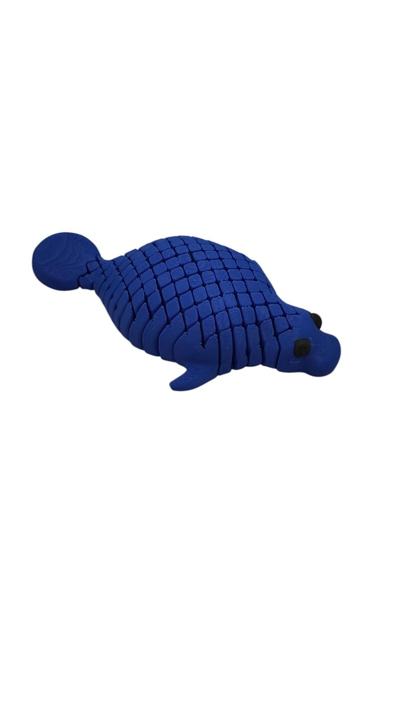 Puede incluir: Figura de foca azul segmentada con ojos negros y cola redondeada. El cuerpo de la foca est&aacute; hecho de numerosos trozos rectangulares peque&ntilde;os, lo que le da un aspecto texturizado. La figura est&aacute; sobre un fondo blanco liso.
