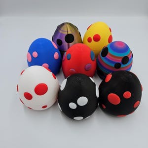 May include: Eight colorful speckled Easter eggs with different patterns and colors, including red, blue, white, black, yellow, and purple.
