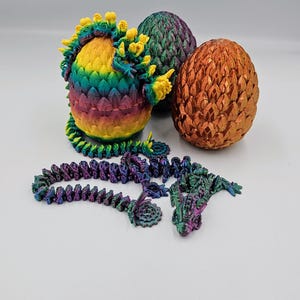 May include: Three dragon eggs, one with a rainbow iridescent finish, one with a green iridescent finish, and one with a copper iridescent finish. A purple iridescent dragon figurine is also included.