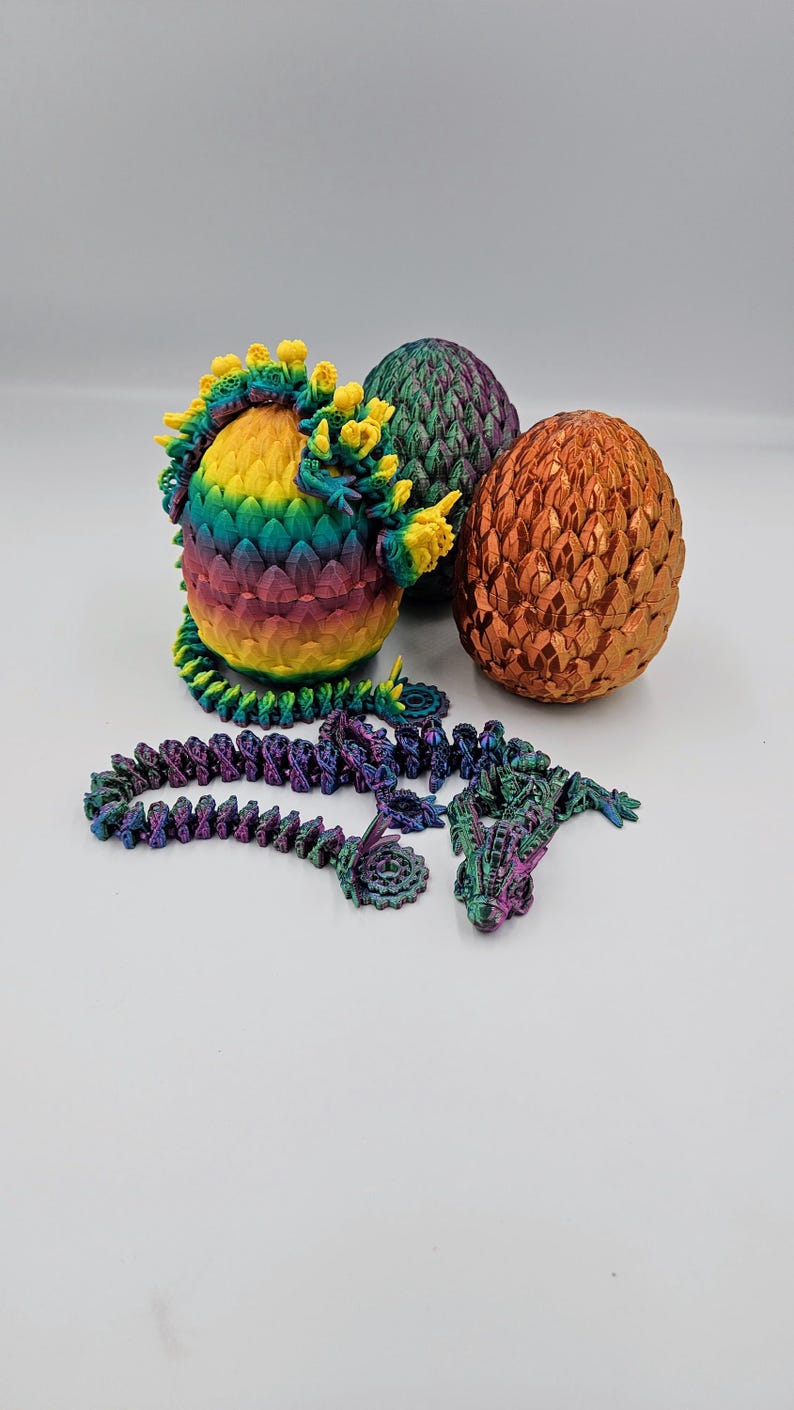 May include: Three dragon eggs, one with a rainbow iridescent finish, one with a green iridescent finish, and one with a copper iridescent finish. A purple iridescent dragon figurine is also included.
