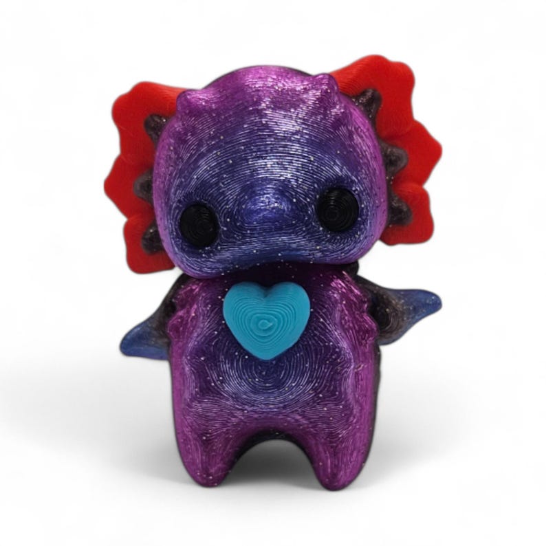May include: A 3D-printed axolotl figurine in shades of purple, blue, and red. The figurine has a heart-shaped design on its chest and black eyes. The axolotl has a textured surface and is standing upright.