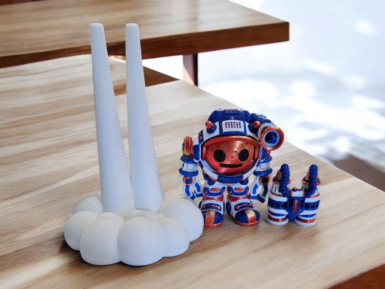 May include: A white ceramic rocket ship with two tall, pointed towers and a cloud-shaped base. A small, blue and red astronaut figurine with a copper helmet stands in front of the rocket.