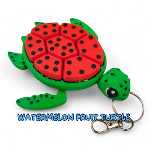 May include: A green and red watermelon fruit turtle keychain. The turtle's shell is made up of watermelon slices with black seeds. The turtle has a green head and feet.
