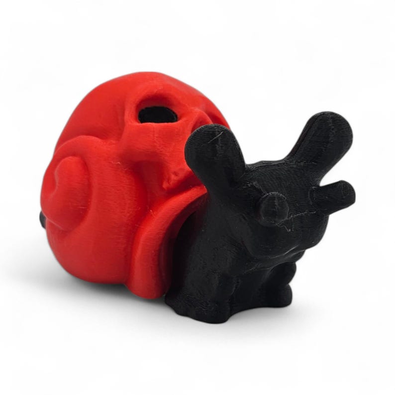 May include: A red skull-shaped object and a black hand. The skull has a smooth texture, while the hand has a rougher appearance. The objects are likely 3D-printed and are set against a white background.
