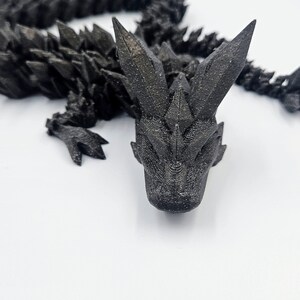 May include: A black 3D printed dragon figurine with a spiky, textured body and a detailed head.