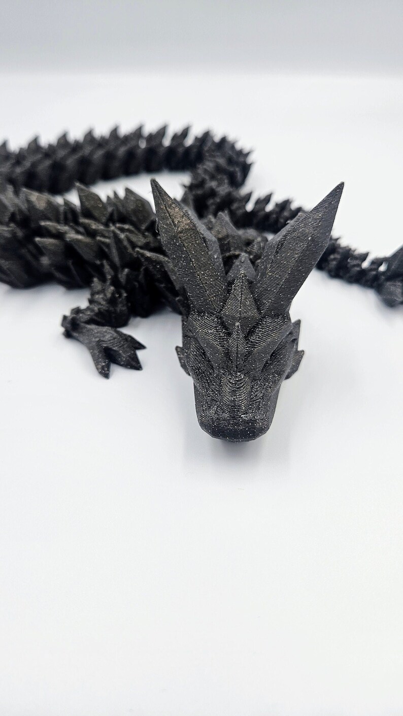 May include: A black 3D printed dragon figurine with a spiky, textured body and a detailed head.