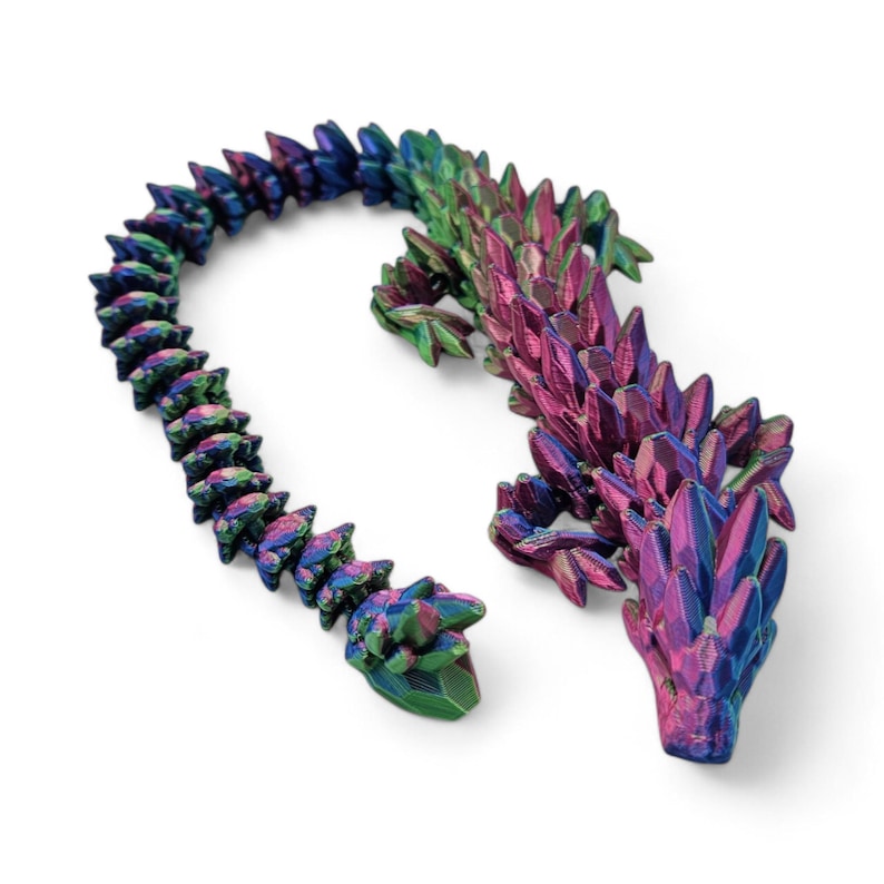 May include: A 3D printed iridescent lizard with a spiky, scaly texture. The lizard is green, blue, and purple with a metallic sheen. The lizard is posed in a curled position with its tail wrapped around its body.