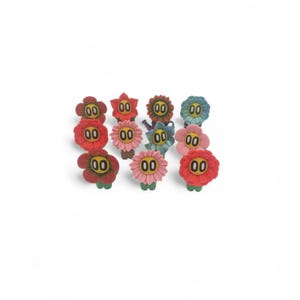 May include: A collection of colorful flower-shaped buttons. The buttons feature various shades of red, pink, blue, and green, with a yellow center and the number "00" printed on each. The buttons are arranged on a white background.