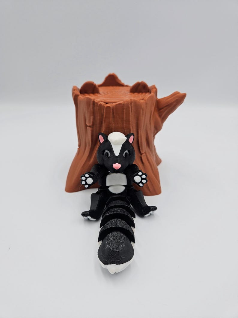May include: A black and white skunk figurine with a segmented tail, sitting on a brown tree stump.