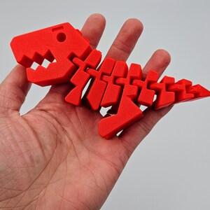 May include: A bright red plastic dinosaur skeleton toy. The skeleton is articulated and can be posed in different positions.