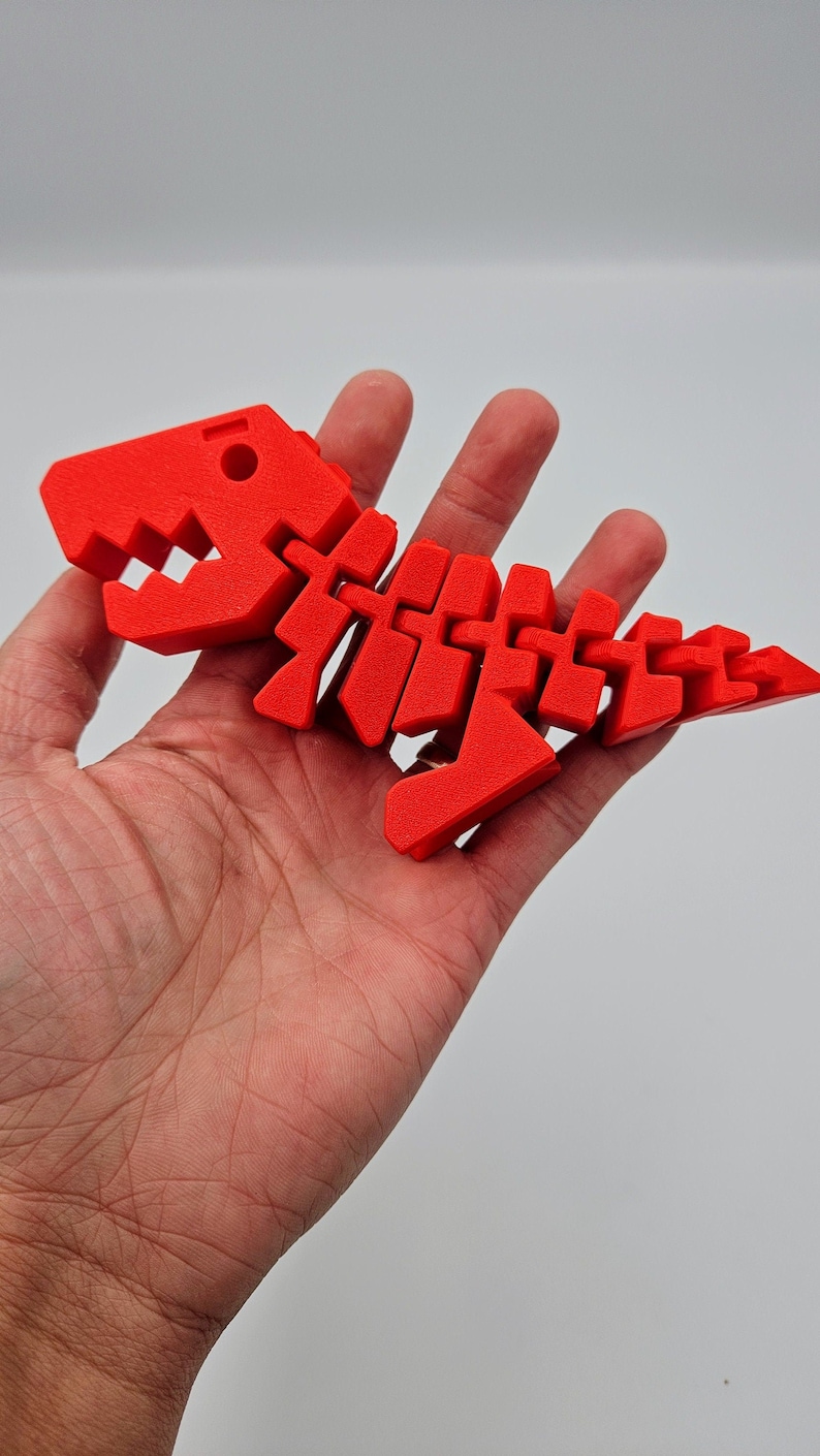 May include: A bright red plastic dinosaur skeleton toy. The skeleton is articulated and can be posed in different positions.