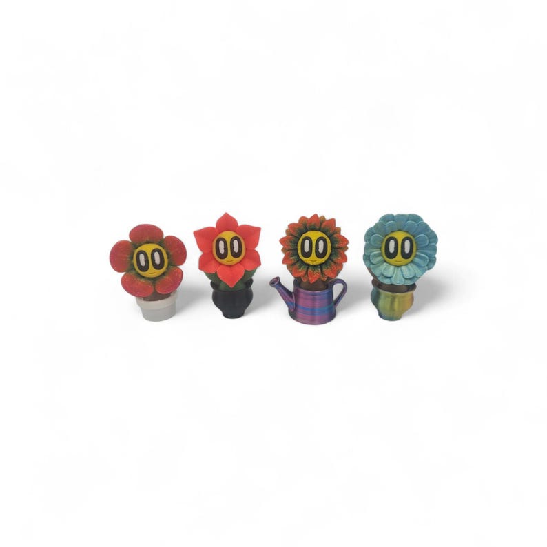 May include: Four colorful flower-shaped figurines with the number "00" in the center of each flower. The flowers are red, orange, and blue, and are in small pots or a watering can. The background is white.