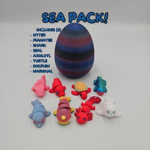K&ouml;nnte beinhalten: Ein Set mit acht bunten Meereslebewesen-Figuren, darunter ein Otter, ein Seekuh, ein Hai, eine Robbe, ein Axolotl, eine Schildkr&ouml;te, ein Delfin und ein Narwal. Die Figuren sind auf einer wei&szlig;en Oberfl&auml;che vor einem blauen und violetten, gesprenkelten eif&ouml;rmigen Beh&auml;lter angeordnet. Der Text "SEA PACK!" ist in gro&szlig;en blauen Buchstaben &uuml;ber dem Ei geschrieben. Der Text "INCLUDES (8)" ist in schwarzen Buchstaben &uuml;ber einer Liste der acht im Set enthaltenen Meereslebewesen geschrieben.
