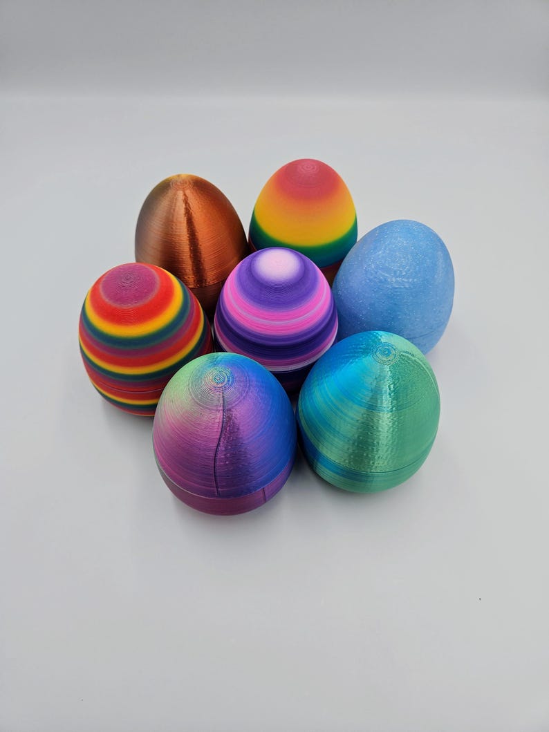 K&ouml;nnte beinhalten: Sechs bunte Ostereier, jedes mit einem anderen Muster und einer anderen Farbe. Die Eier sind aus Kunststoff und haben eine glatte, gl&auml;nzende Oberfl&auml;che. Die Farben umfassen Regenbogen, Lila, Blau, Gr&uuml;n und Kupfer.